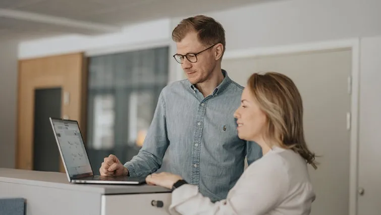 image of two people looking at a laptop screen